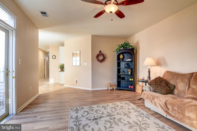 living room with light wood finished floors, plenty of natural light, visible vents, and baseboards