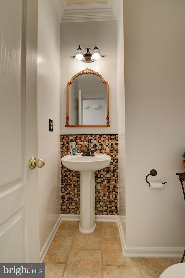 bathroom featuring baseboards, crown molding, a sink, and tile patterned floors