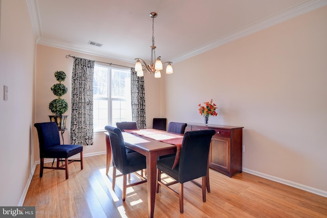 dining area featuring baseboards, light wood-style flooring, visible vents, and crown molding