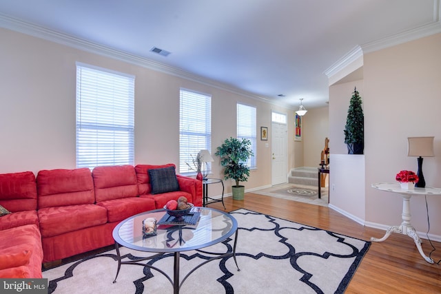 living room featuring visible vents, baseboards, stairs, light wood-type flooring, and crown molding