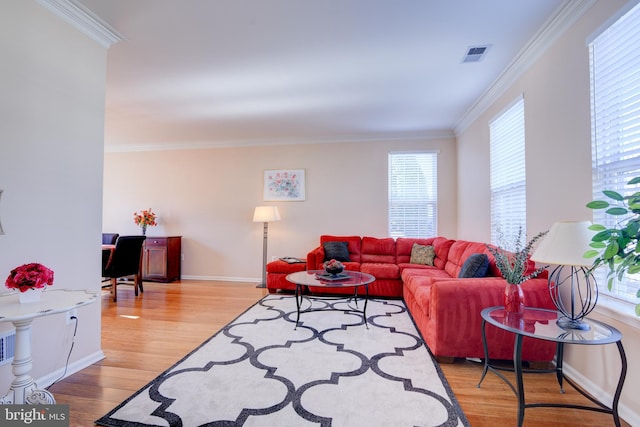 living area featuring a wealth of natural light, light wood-type flooring, visible vents, and crown molding