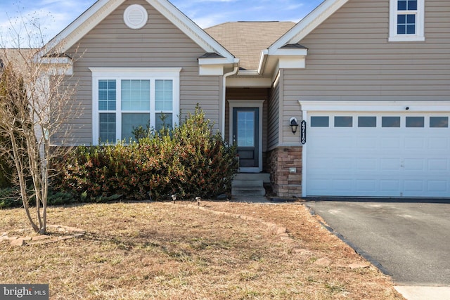 view of front of house featuring a garage, stone siding, aphalt driveway, and a front lawn