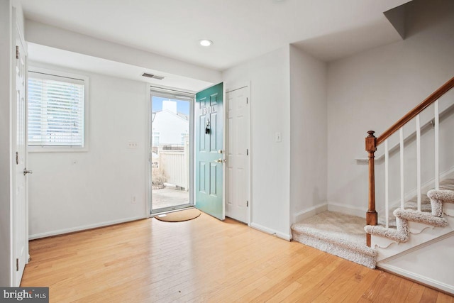 entrance foyer featuring hardwood / wood-style floors, stairway, visible vents, and baseboards