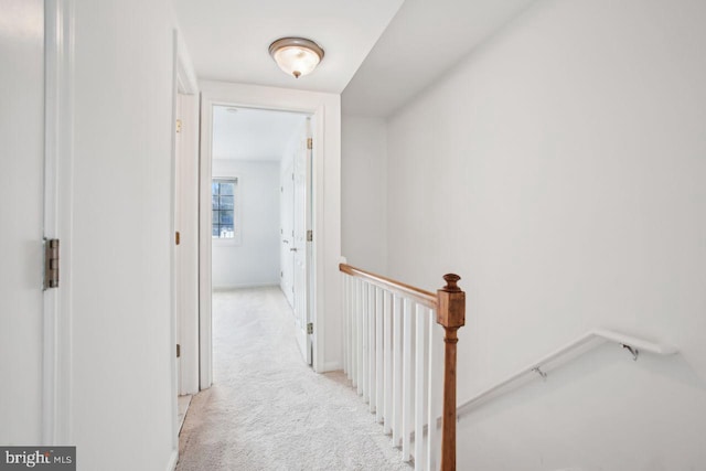 hall with baseboards, an upstairs landing, and light colored carpet