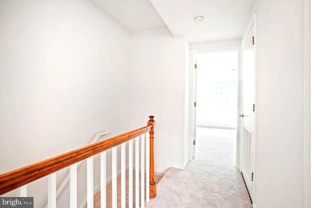 hall featuring carpet flooring and an upstairs landing