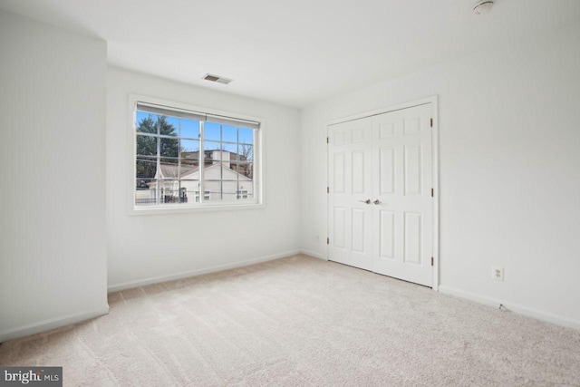 unfurnished bedroom with a closet, carpet flooring, visible vents, and baseboards