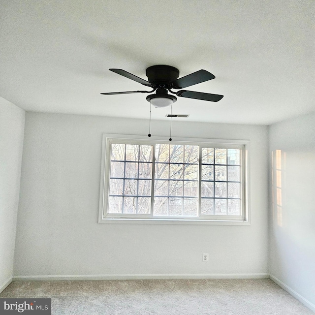 spare room featuring a ceiling fan, carpet, visible vents, and baseboards