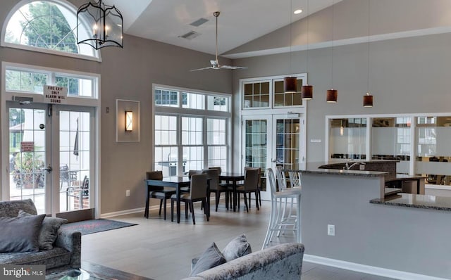 living area featuring high vaulted ceiling, a wealth of natural light, french doors, and light wood-style flooring