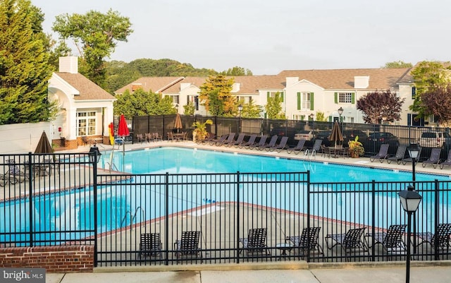 community pool featuring a residential view, fence, and a patio