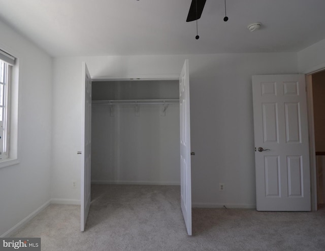 unfurnished bedroom with ceiling fan, baseboards, a closet, and carpet flooring