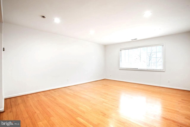 spare room featuring recessed lighting, wood finished floors, visible vents, and baseboards