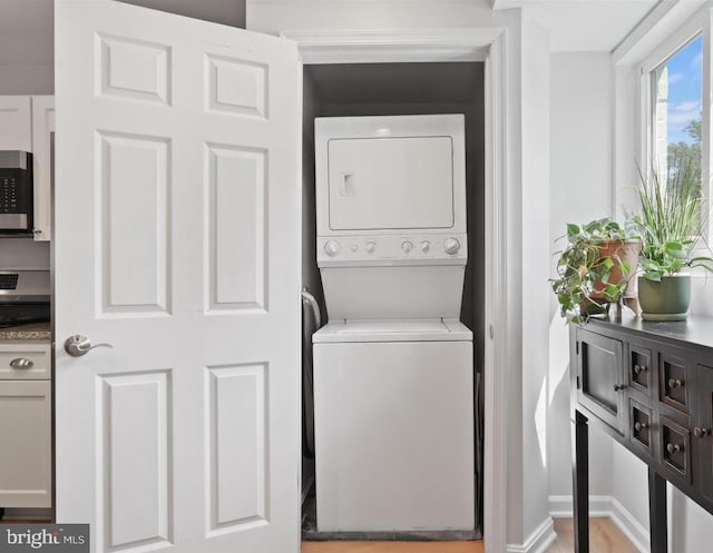 laundry area featuring stacked washer and dryer, laundry area, and baseboards