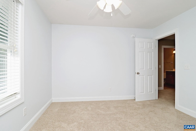 empty room with light carpet, baseboards, and a ceiling fan