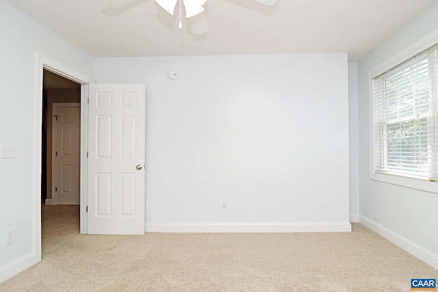 spare room with baseboards, a ceiling fan, and light colored carpet