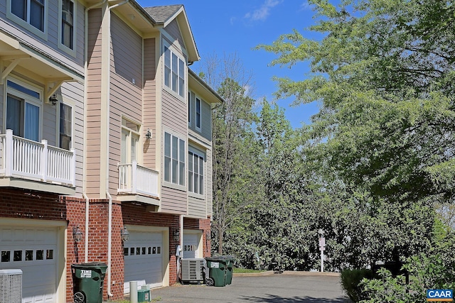 view of building exterior featuring an attached garage and cooling unit