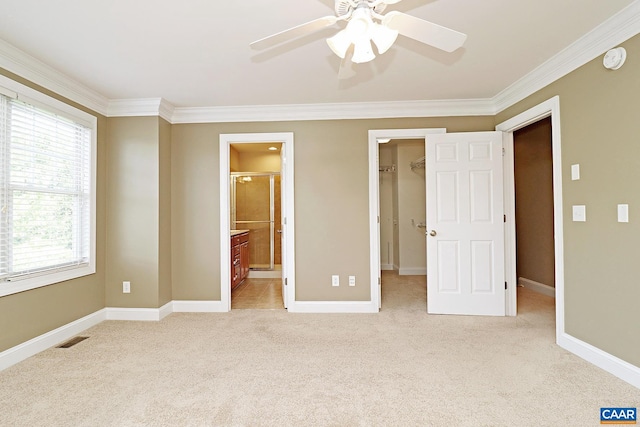 unfurnished bedroom featuring light carpet, a spacious closet, visible vents, and crown molding