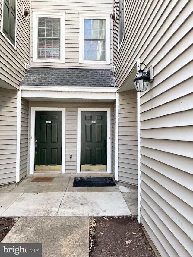 view of exterior entry featuring a shingled roof