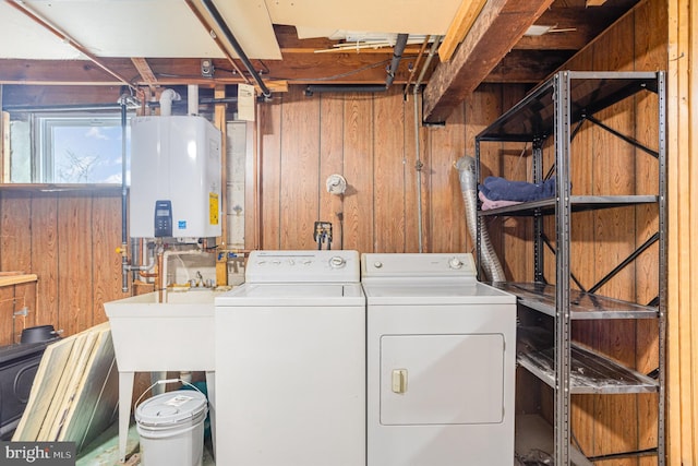 laundry area with laundry area, water heater, wood walls, and independent washer and dryer