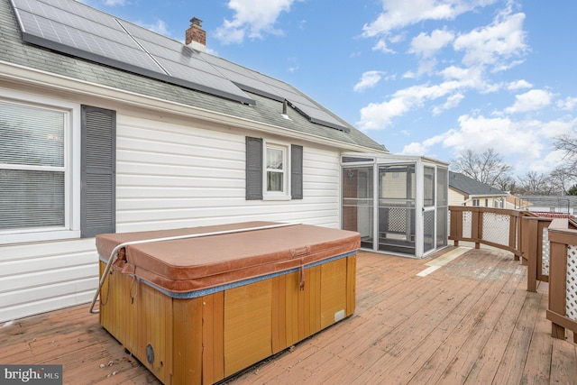 wooden deck with a sunroom and a hot tub