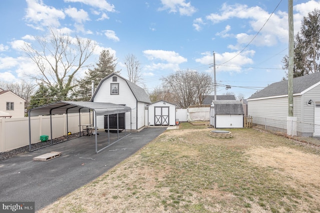 view of yard featuring a storage shed, fence, a carport, and an outdoor structure