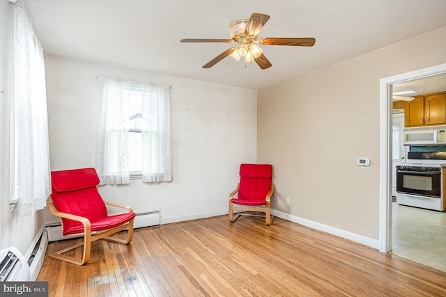 sitting room featuring baseboards, a ceiling fan, and light wood-style floors