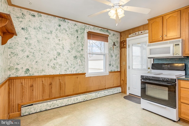 kitchen featuring a wainscoted wall, wallpapered walls, stove, and white microwave