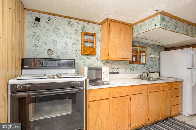 kitchen featuring light countertops, wallpapered walls, a sink, and stove