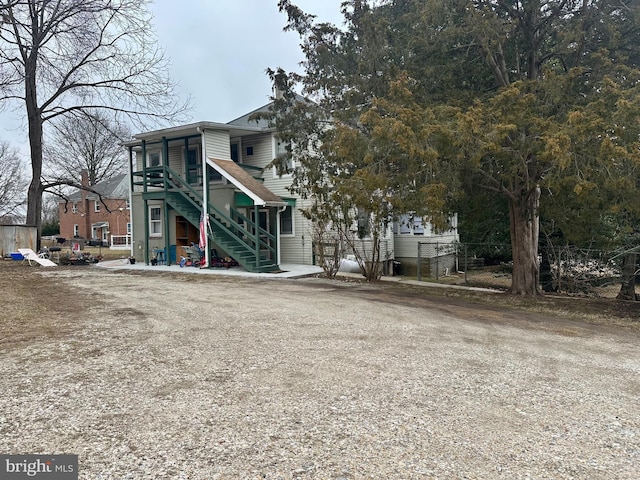 rear view of property featuring stairs and fence