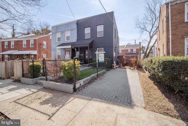 view of property with brick siding, a fenced front yard, and a residential view