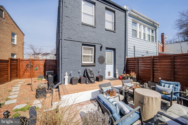 rear view of house featuring an outdoor living space with a fire pit, brick siding, and a fenced backyard