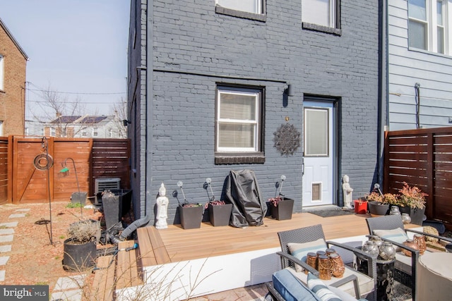 back of property featuring a deck, brick siding, and a fenced backyard