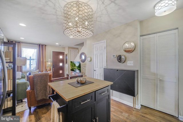 kitchen with recessed lighting, dark cabinets, wood finished floors, baseboards, and wooden counters