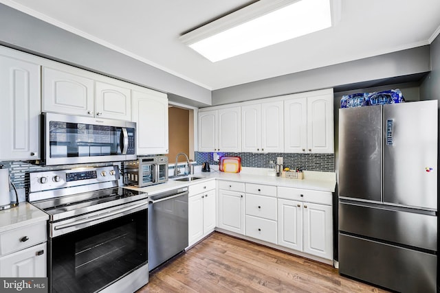 kitchen with light countertops, light wood-style flooring, appliances with stainless steel finishes, white cabinetry, and a sink