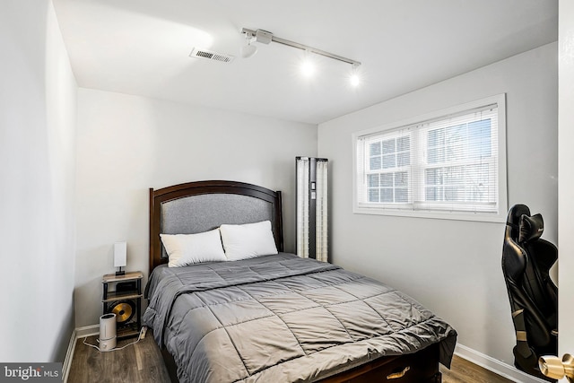 bedroom featuring visible vents, baseboards, and wood finished floors