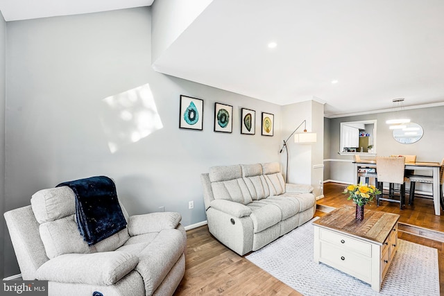 living area featuring crown molding, baseboards, and wood finished floors