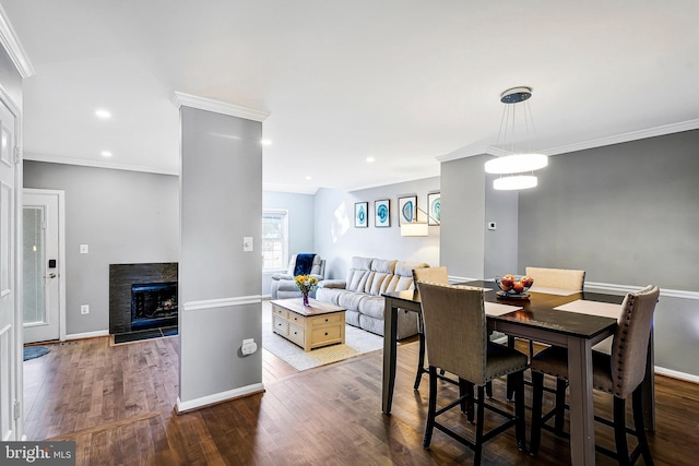 dining area featuring dark wood-type flooring, a fireplace, crown molding, and baseboards