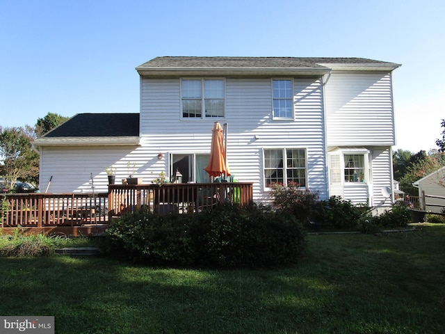 rear view of house featuring a deck and a yard