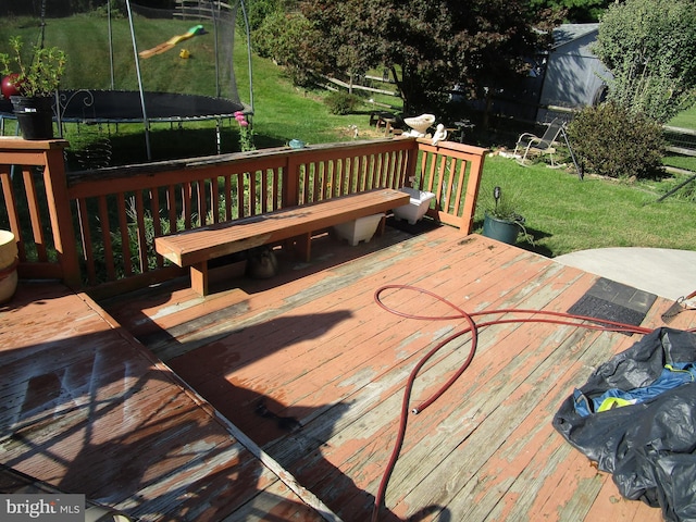 deck featuring a trampoline and a lawn