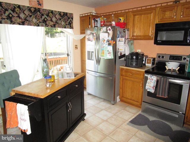 kitchen with light tile patterned floors, light countertops, appliances with stainless steel finishes, dark cabinetry, and brown cabinetry