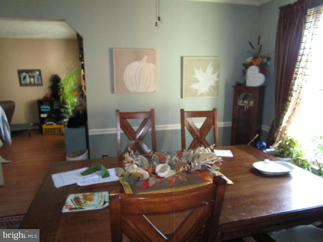 dining area with arched walkways and wood finished floors