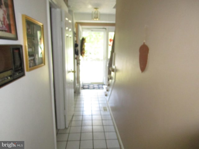 corridor with baseboards and light tile patterned floors