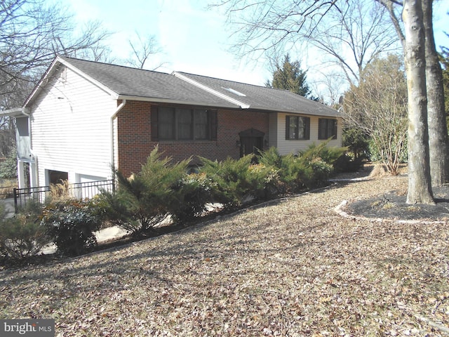 view of front facade with a shingled roof and brick siding