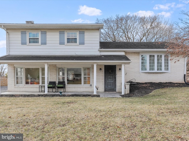 split level home with a shingled roof, a front lawn, and brick siding