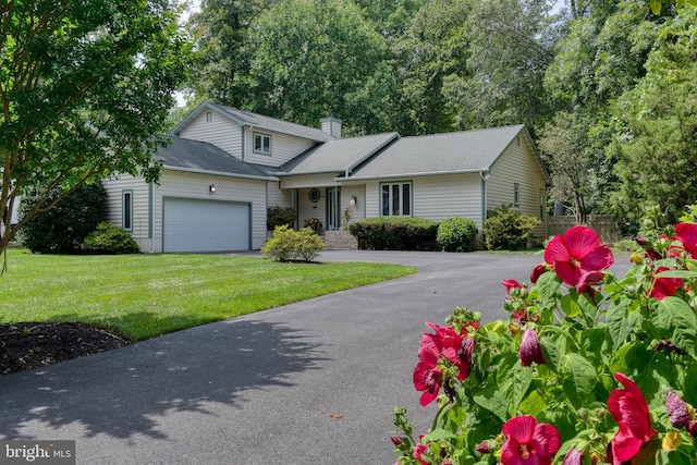 traditional-style home with a garage, a front yard, fence, and aphalt driveway