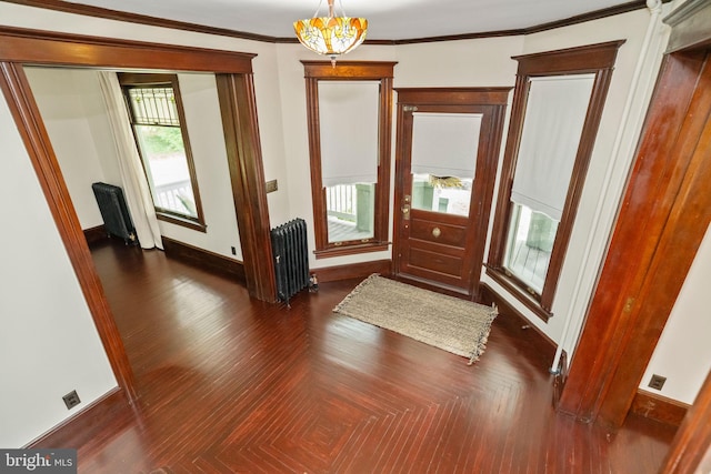 entrance foyer with a chandelier, baseboards, parquet floors, radiator heating unit, and crown molding