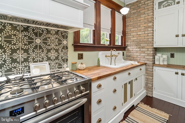 kitchen featuring decorative light fixtures, glass insert cabinets, gas stove, white cabinets, and wood counters