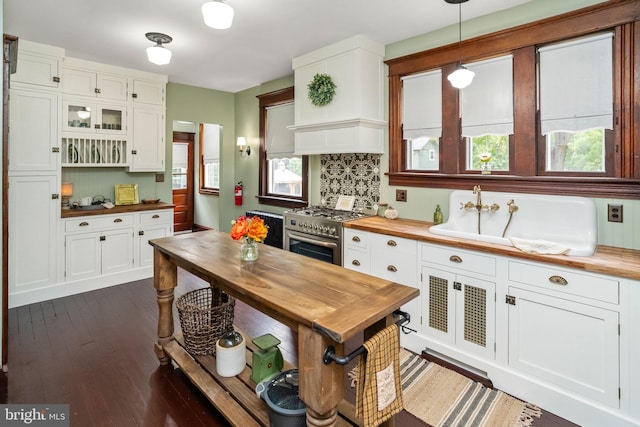 kitchen featuring decorative light fixtures, wood counters, white cabinets, stainless steel range, and glass insert cabinets