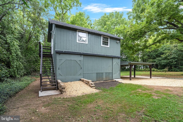 view of barn featuring driveway, stairway, and a carport