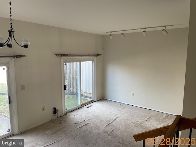 carpeted empty room featuring plenty of natural light, visible vents, and track lighting