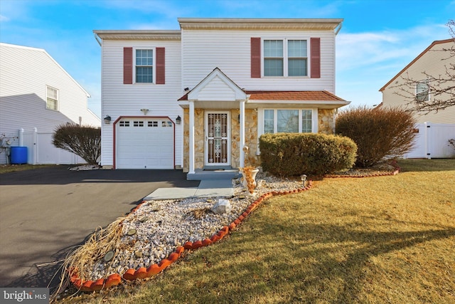 traditional home with a garage, stone siding, aphalt driveway, fence, and a front lawn